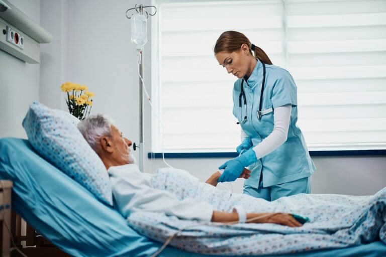 Mid adult nurse checking IV drip of senior patient at hospital ward