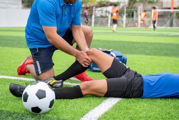 Footballer wearing a blue shirt, black pants injured in the lawn during the race